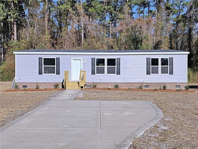 a front view of a house with a yard and trees