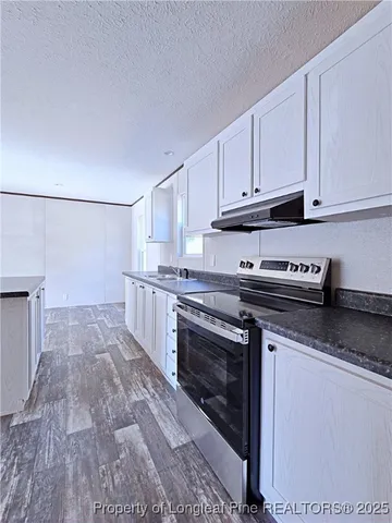 a kitchen with granite countertop a stove top oven and cabinets