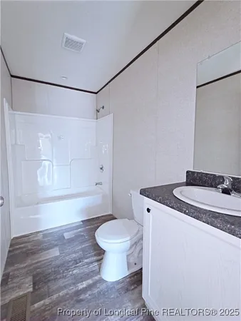 an empty room with wooden floor closet and windows