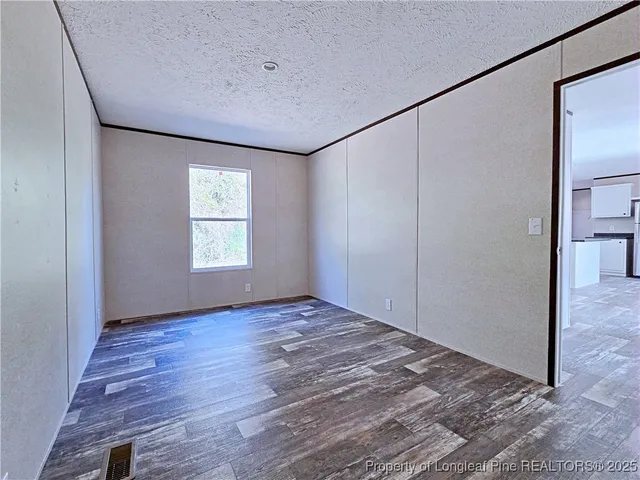 a view of an empty room with a window and hardwood floor