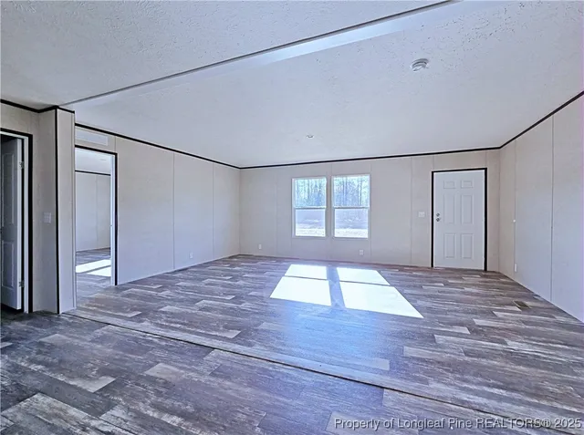 a view of empty room with wooden floor and window