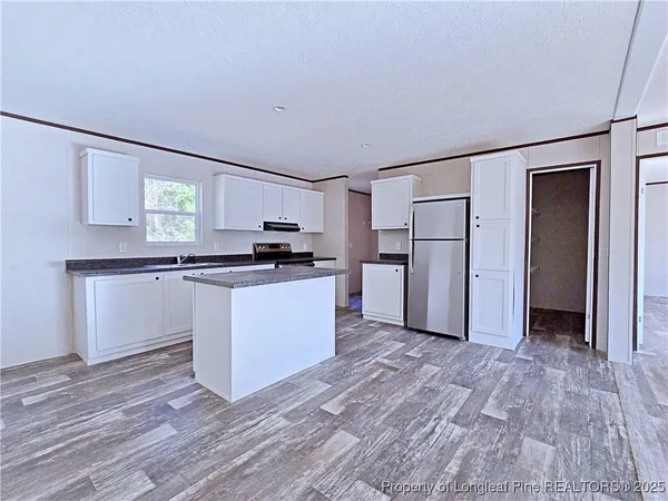 a kitchen with white cabinets and refrigerator