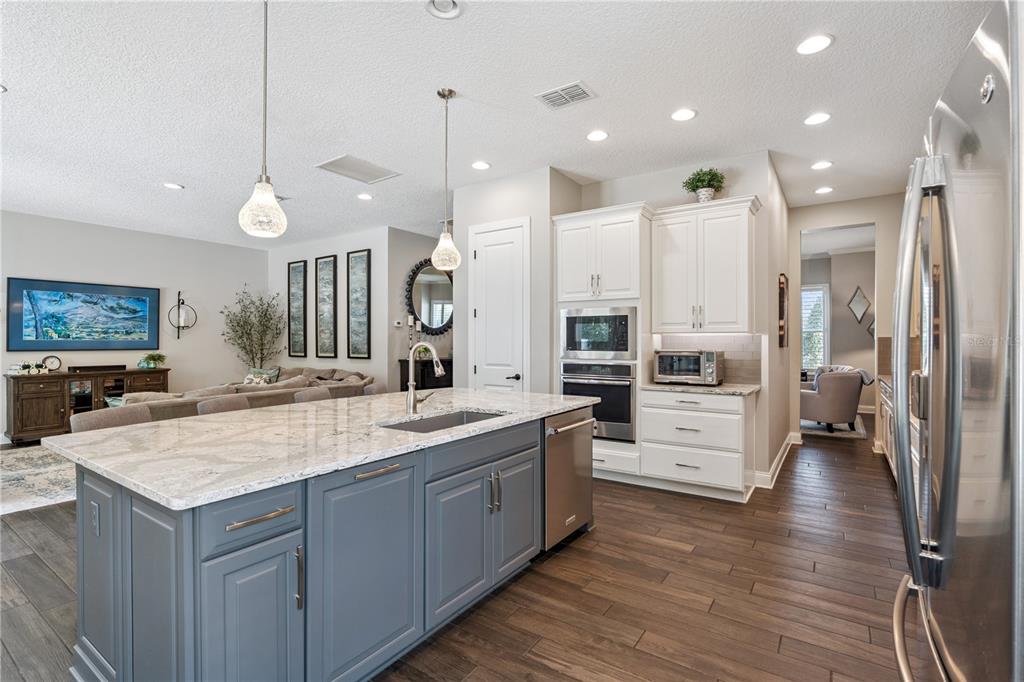 352 Moonbeam Loop Oviedo, FL 32765 - Photo 10 of 64 a large kitchen with stainless steel appliances kitchen island granite countertop a large counter top a stove a sink a refrigerator and living room view