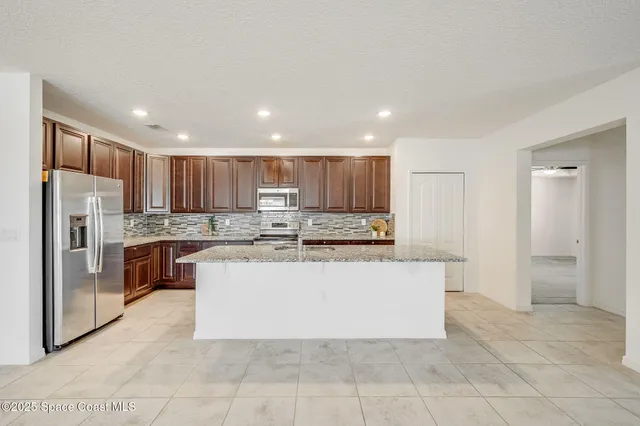 a large kitchen with a large counter top stainless steel appliances and cabinets