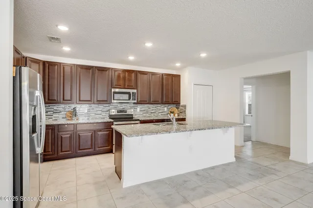 a kitchen with stainless steel appliances granite countertop refrigerator sink and stove