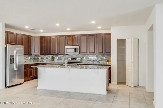 a kitchen with stainless steel appliances granite countertop a stove a sink and a refrigerator