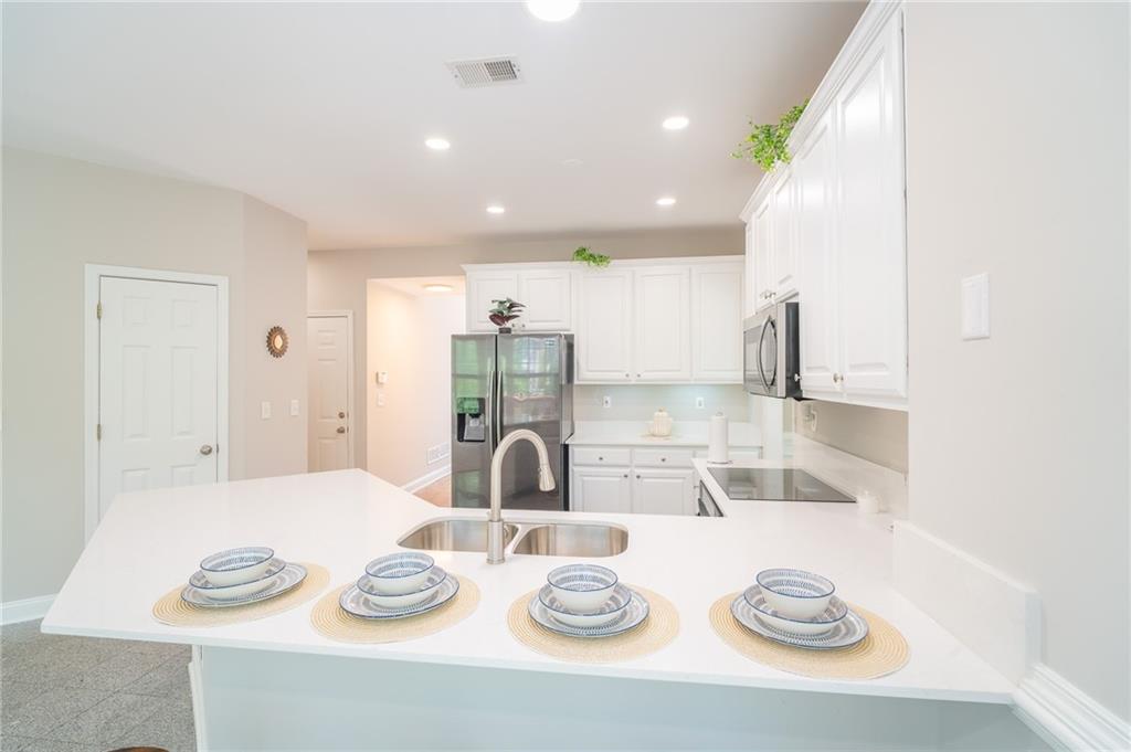 3819 Meandering Way Southwest Lilburn, GA 30047 - Photo 12 of 27 a kitchen with stainless steel appliances wooden floor dining table and chairs
