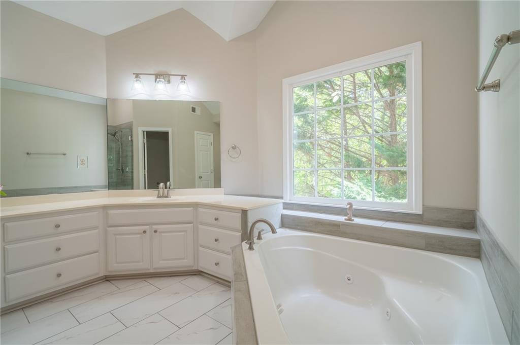 3819 Meandering Way Southwest Lilburn, GA 30047 - Photo 16 of 27 a spacious bathroom with a tub sink and mirror
