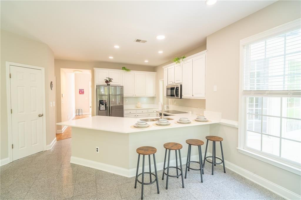 3819 Meandering Way Southwest Lilburn, GA 30047 - Photo 7 of 27 a kitchen with stainless steel appliances granite countertop a stove a sink a refrigerator and white cabinets with wooden floor