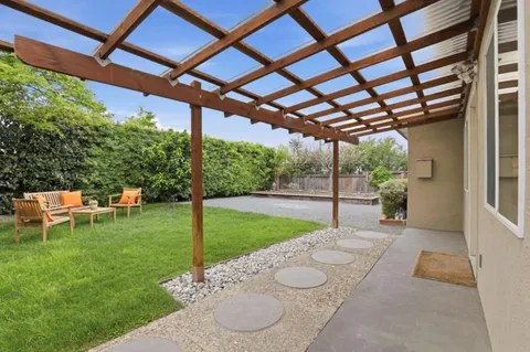 a view of a chair and table in backyard of the house