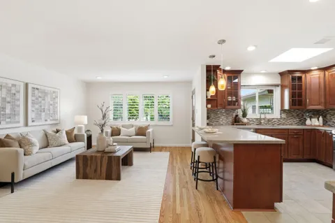 a living room with furniture kitchen view and a large window
