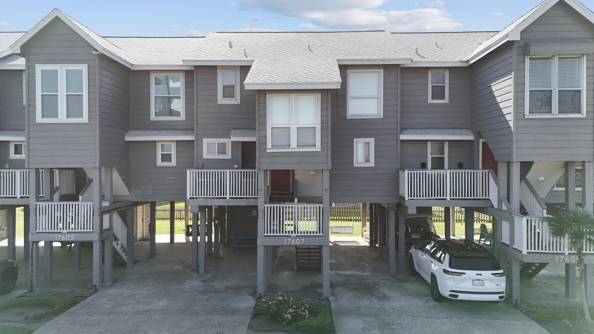 17607 Termini-San Luis Pass Road Galveston, TX 77554 - Photo 39 of 42 This view highlights the row of well-maintained townhomes, each with elevated porches for enjoying the coastal breeze. The driveway offers ample space for parking, making it convenient for guests and residents alike.