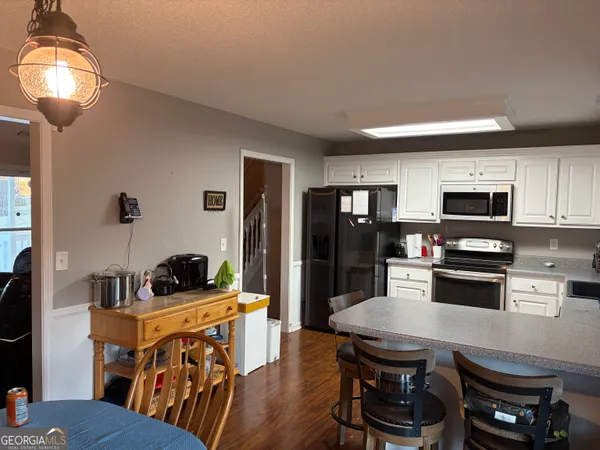 a kitchen with stainless steel appliances granite countertop a stove a refrigerator a sink a dining table and chairs with wooden floor