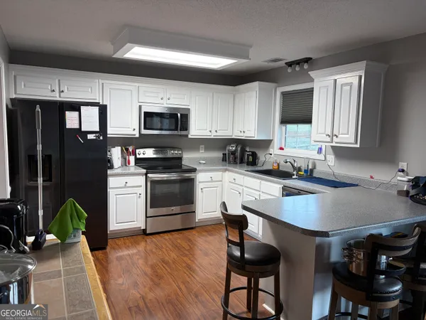 a kitchen with granite countertop a stove top oven a sink dishwasher a dining table and chairs with wooden floor