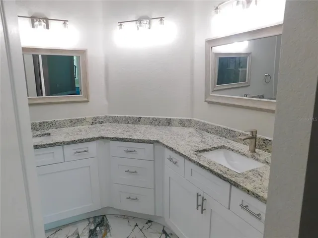 a bathroom with a granite countertop sink and mirror