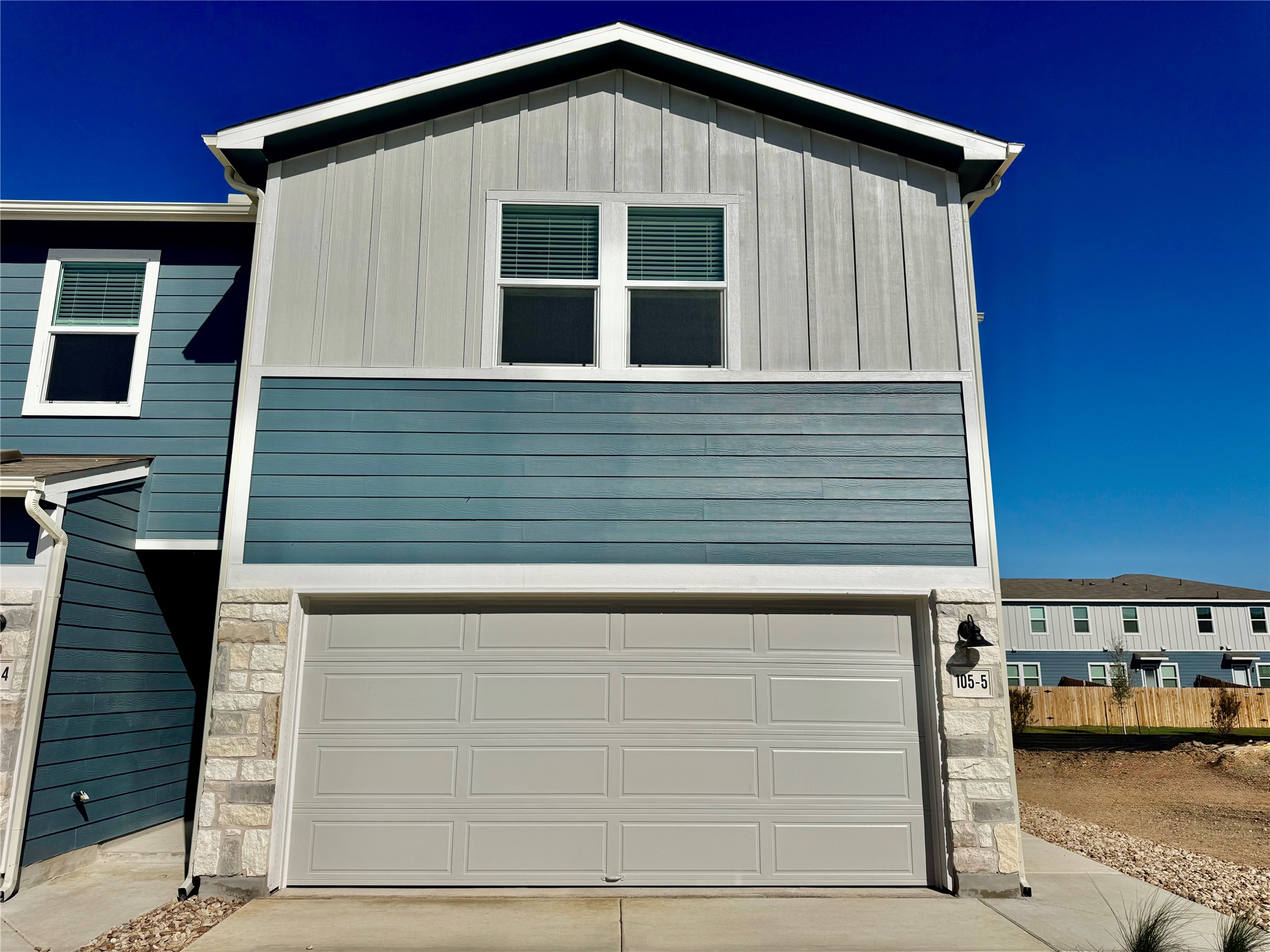 View of front facade featuring stone siding, board and batten siding, and a garage