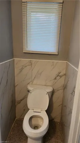 a white toilet sitting next to a small window