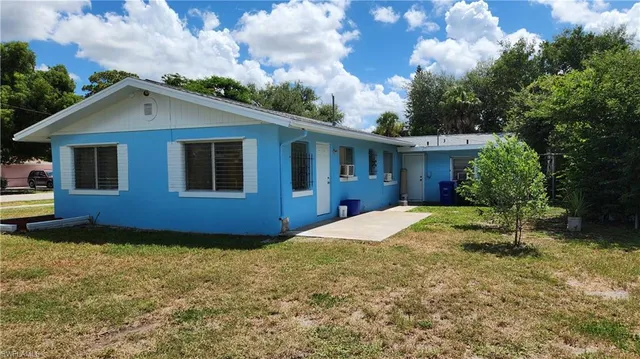 a view of house with yard and trees in the background