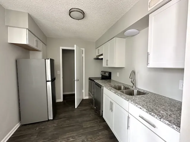 a kitchen with a sink a refrigerator and cabinets