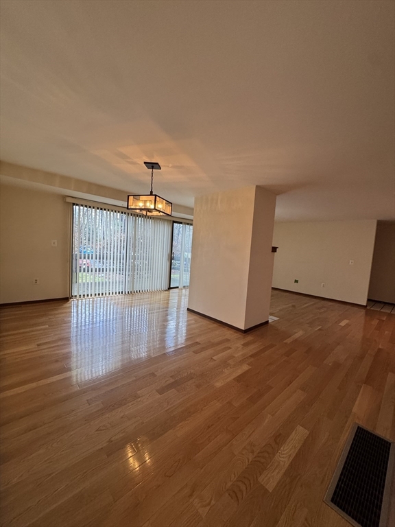 445 Old Stone Brook, Unit 445 Acton, MA 01718 - Photo 5 of 16 wooden floor in an empty room with a window