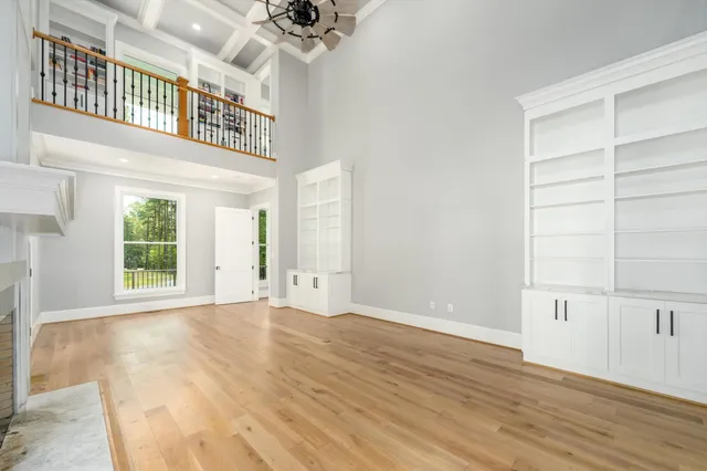 a view of a hallway with wooden floor and a bathroom