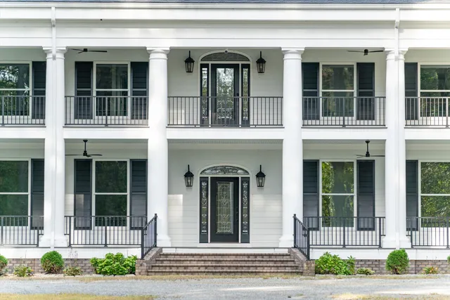 a view of a house with a small yard plants and large tree