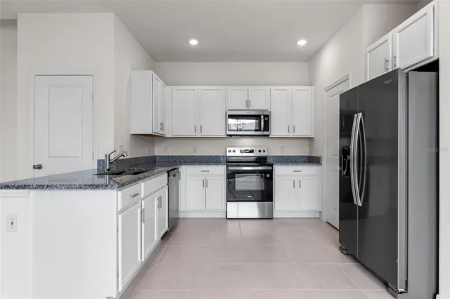 a kitchen with stainless steel appliances granite countertop a refrigerator stove and microwave