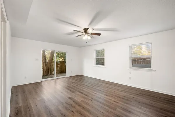 an empty room with wooden floor and ceiling fan
