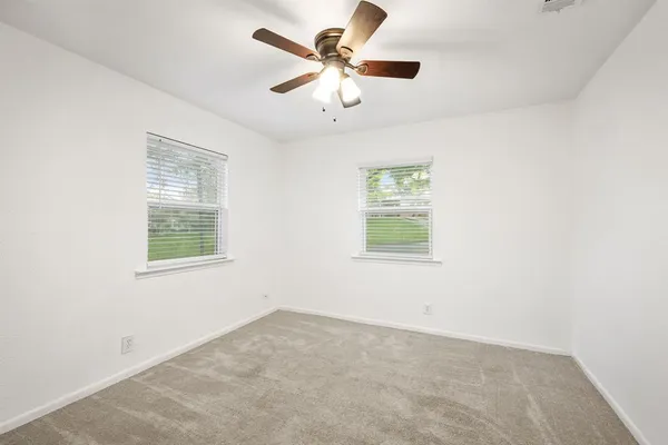 an empty room with windows and fan