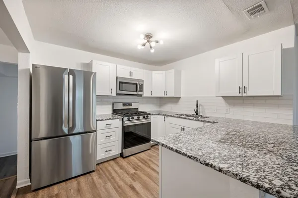a kitchen with granite countertop a refrigerator stove and microwave