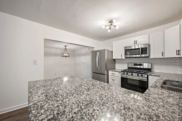 a kitchen with stainless steel appliances granite countertop a refrigerator sink and white cabinets