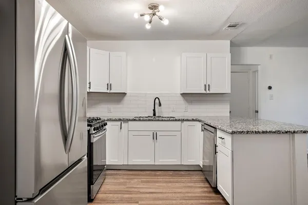 a kitchen with granite countertop a refrigerator window and white cabinets