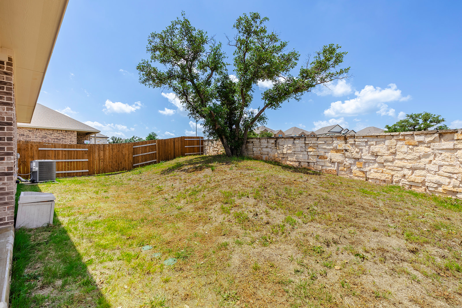 900 Balsora Cove Georgetown, TX 78628 - Photo 29 of 39 A private, sloped yard features a mature shade tree and both wood and stone fencing.