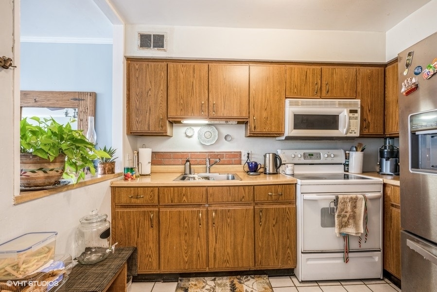 5415 North Sheridan Road, Unit 1015 Chicago, IL 60640 - Photo 6 of 10 a kitchen with a stove a sink and a microwave
