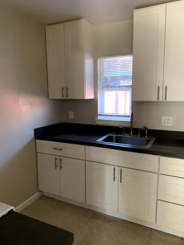 a kitchen with granite countertop white cabinets and sink