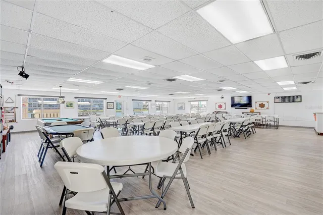 a dining hall with stainless steel appliances lots of wooden furniture a table and chairs