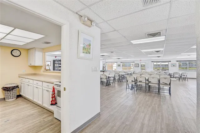 a open kitchen with stainless steel appliances granite countertop a dining table chairs and a stove top oven