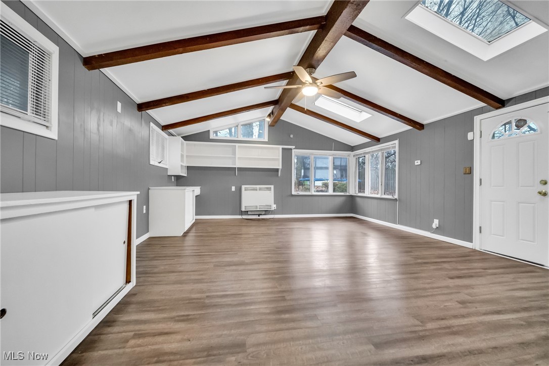 1605 Laclede Road Cleveland, OH 44121 - Photo 13 of 40 Unfurnished living room with visible vents, heating unit, wood finished floors, and lofted ceiling with skylight