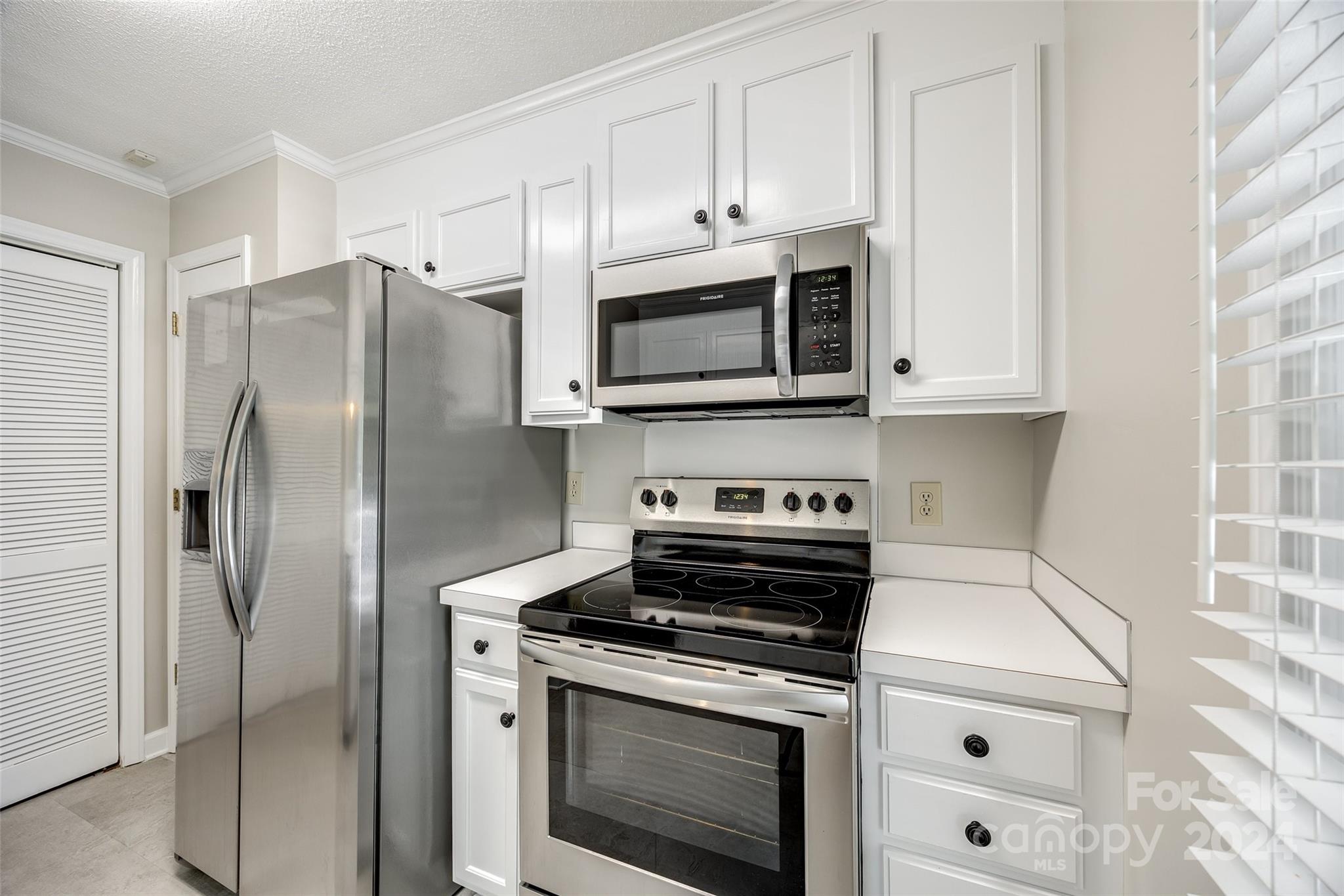 1711 Robinwood Road Gastonia, NC 28054 - Photo 14 of 25 a kitchen with stainless steel appliances white cabinets white stove a microwave and a refrigerator