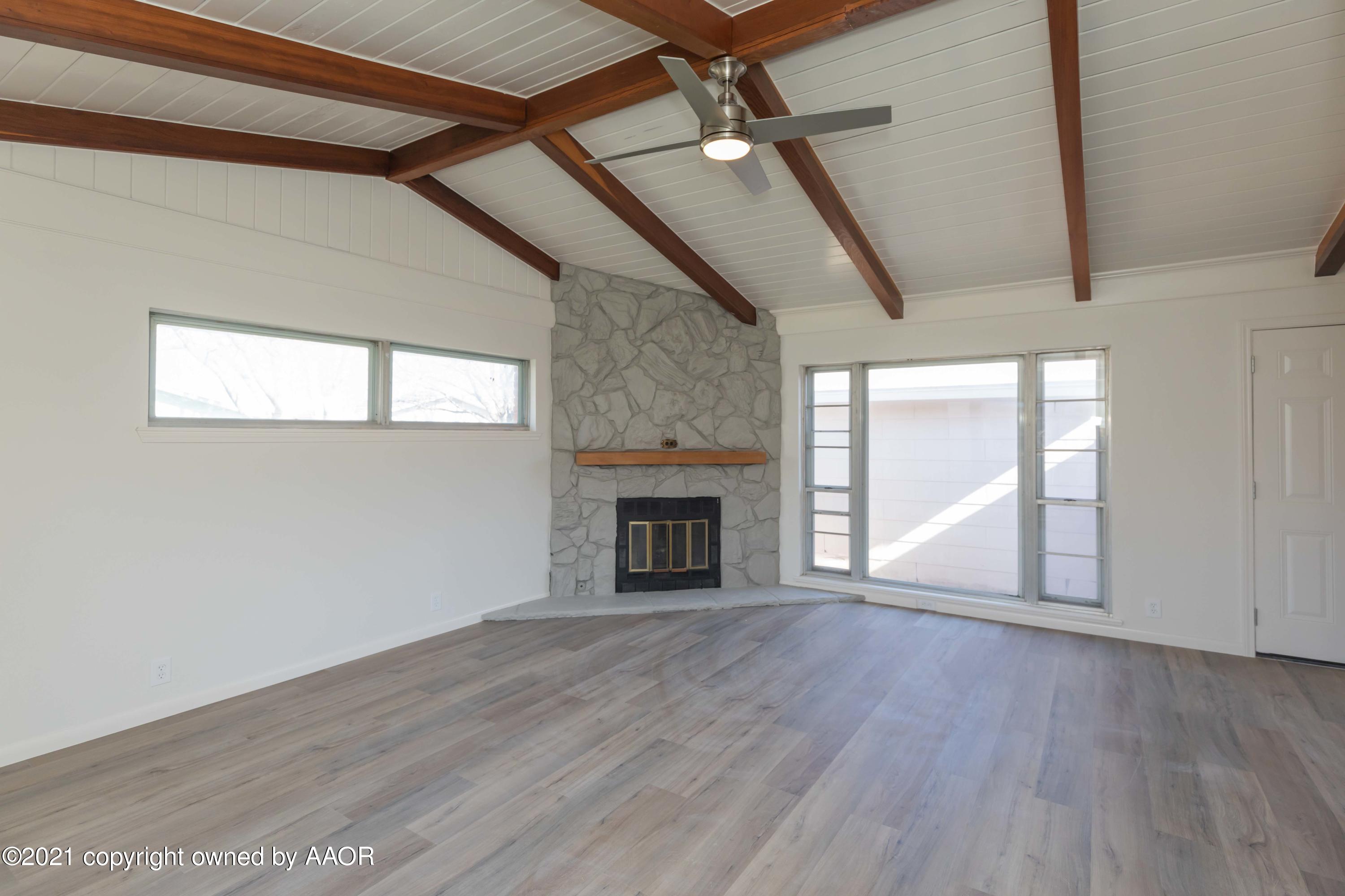 4702 South Rusk Street Amarillo, TX 79110 - Photo 6 of 36 an empty room with wooden floor fireplace and windows