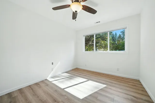 an empty room with a window and a ceiling fan