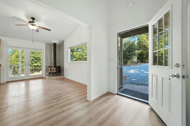 an empty room with wooden floor fan and windows