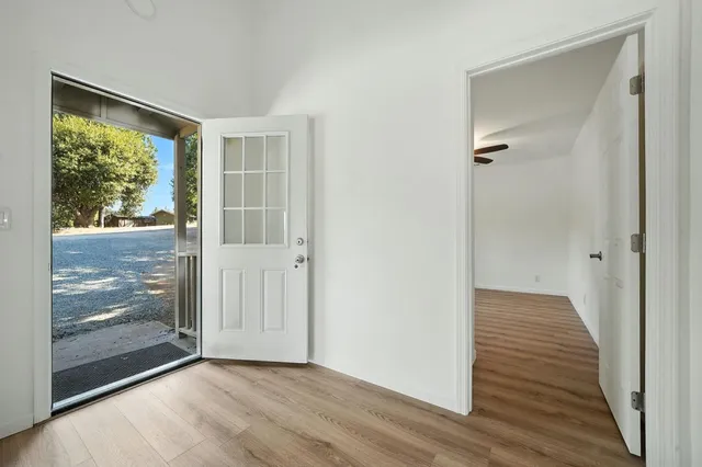 a view of an empty room with wooden floor and a window