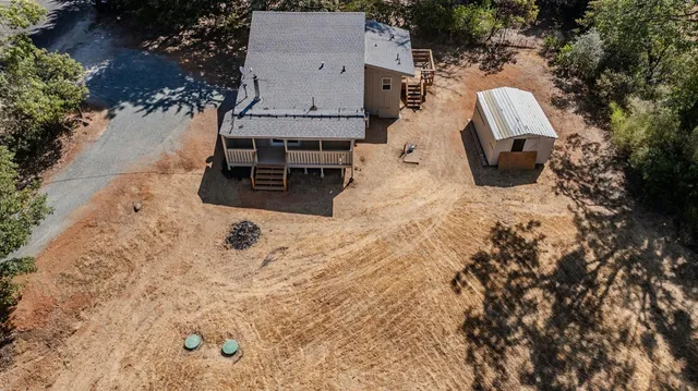 an aerial view of a house with backyard and trees