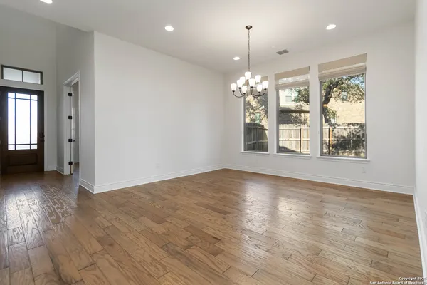a view of an empty room with window and wooden floor