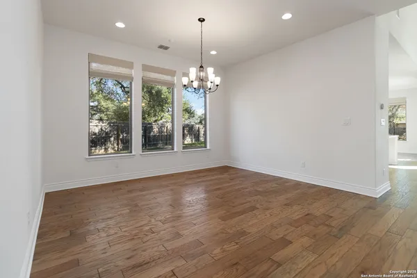 a view of an empty room with window and wooden floor