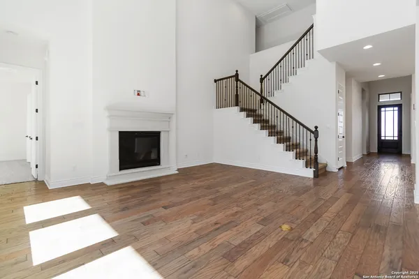 a view of an empty room with wooden floor and a fireplace