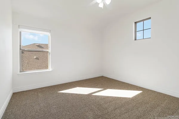 a view of an empty room and a chandelier fan