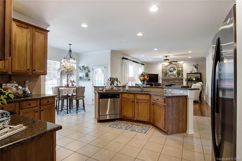785 Fairway Point Drive Tega Cay, SC 29708 - Photo 14 of 46 a kitchen with stainless steel appliances kitchen island granite countertop a refrigerator a sink a dining table and chairs