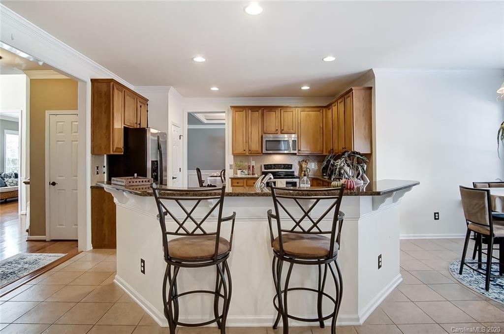 785 Fairway Point Drive Tega Cay, SC 29708 - Photo 10 of 46 a kitchen with stainless steel appliances a table and chairs in it